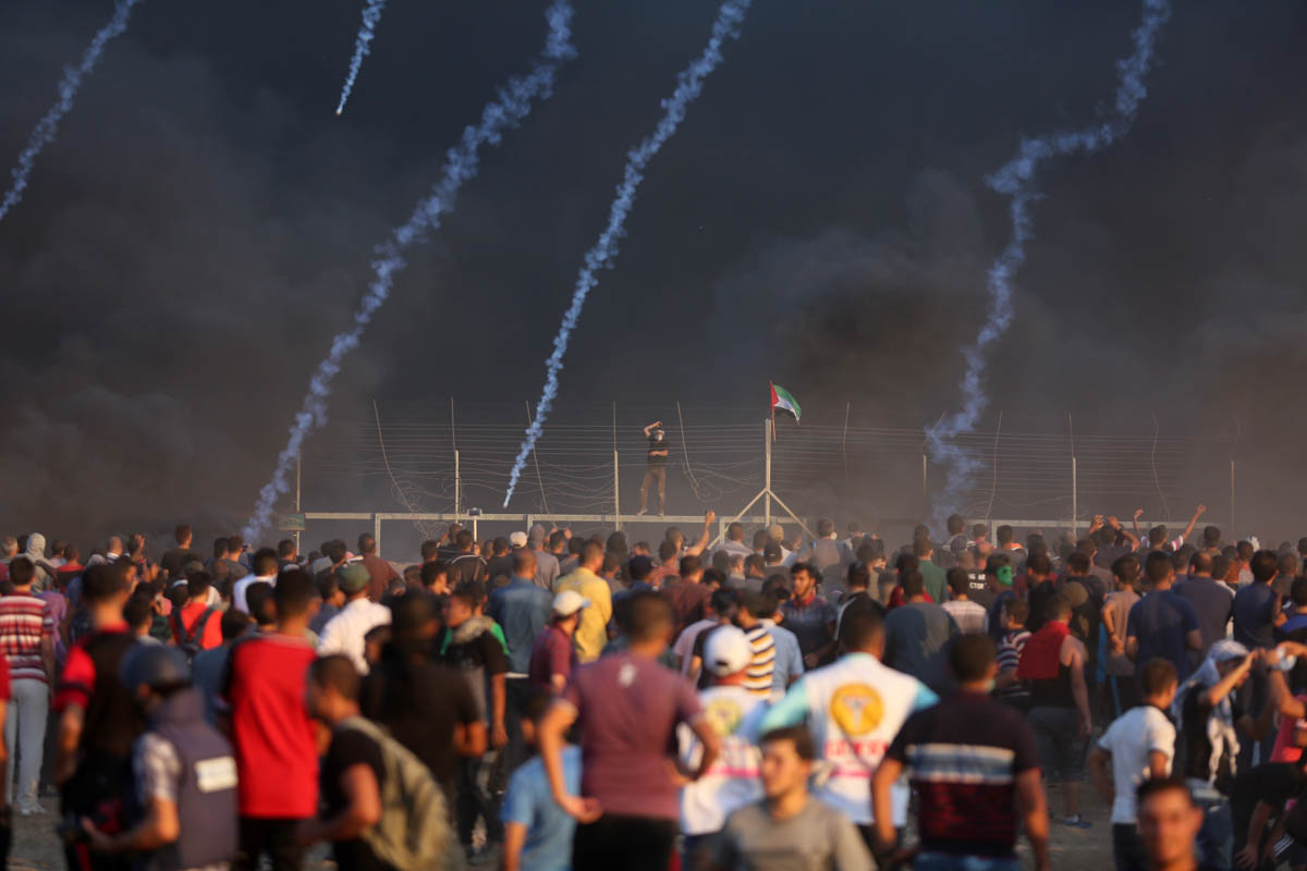 Gazans seen during the Great March of Return at the Gaza-Israel border fence, under fire from tear gas